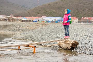 Image showing Little girl is undecided at the beginning of flimsy crossing a stream and looking at the other side