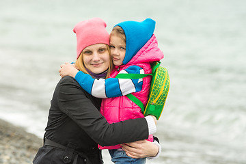 Image showing Mom and daughter in warm clothing standing arm in arm on the beach