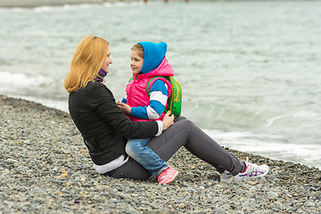 Image showing Mother and daughter tenderly looking at each other sitting on the beach on a cool day