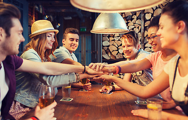 Image showing happy friends with drinks and hands on top at bar