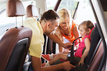 Image showing happy parents fastening child with car seat belt