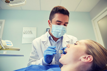 Image showing male dentist in mask checking female patient teeth