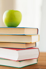 Image showing close up of books and green apple on wooden table