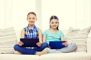 Image showing happy girls with tablet pc sitting on sofa at home