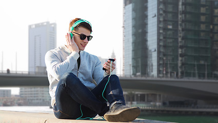 Image showing happy young man in headphones with smartphone