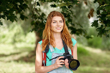 Image showing happy woman with backpack and camera outdoors