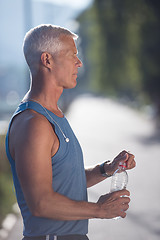 Image showing senior jogging man drinking fresh water from bottle