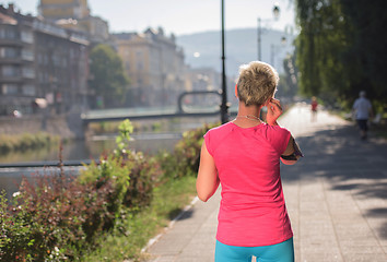 Image showing jogging woman setting phone before jogging