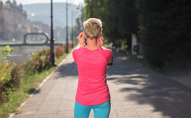 Image showing jogging woman setting phone before jogging