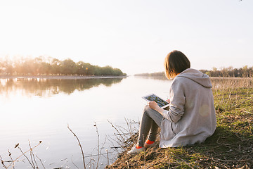 Image showing girl working with tablet at the river