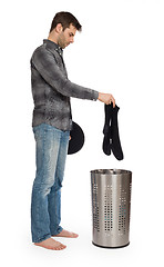 Image showing Young man putting a dirty socks in a laundry basket