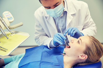 Image showing male dentist in mask checking female patient teeth