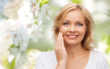 Image showing smiling woman in white t-shirt touching her face