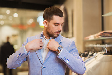 Image showing young man trying jacket on in clothing store