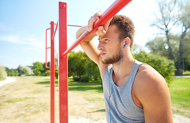 Image showing young man with earphones and horizontal bar