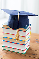 Image showing close up of books and mortarboard on wooden table