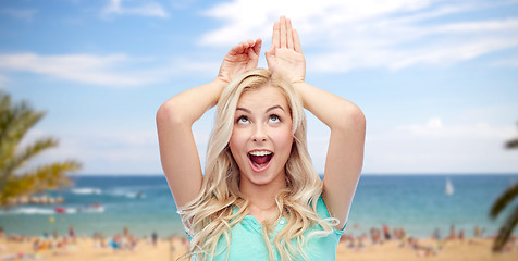 Image showing happy smiling young woman making bunny ears