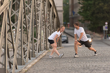 Image showing couple warming up and stretching before jogging