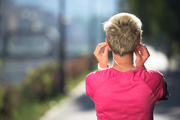 Image showing jogging woman setting phone before jogging