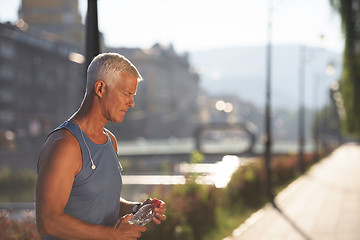 Image showing senior jogging man drinking fresh water from bottle