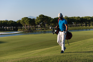 Image showing golf player walking and carrying bag