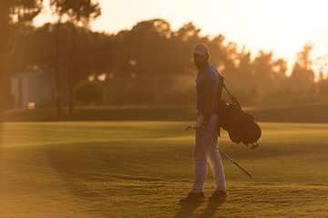 Image showing golfer  walking and carrying golf  bag at beautiful sunset