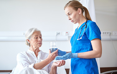 Image showing nurse giving medicine to senior woman at hospital