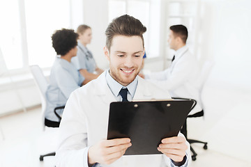 Image showing happy doctor with tablet pc over team at clinic