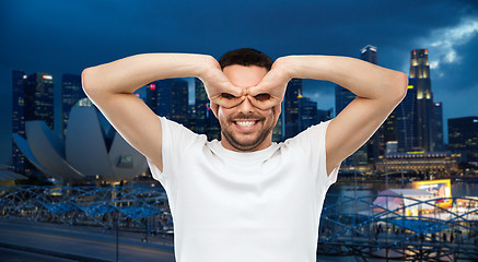 Image showing man making finger glasses over city background