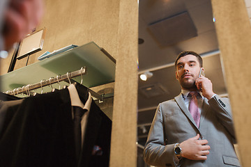 Image showing man calling on smartphone at clothing store mirror