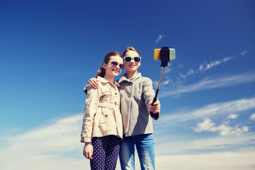 Image showing happy girls with smartphone selfie stick