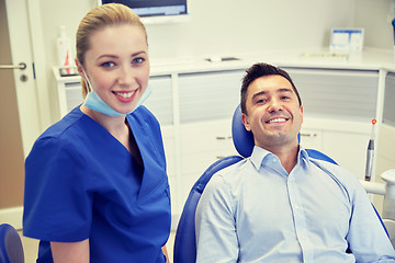 Image showing happy female dentist with man patient at clinic