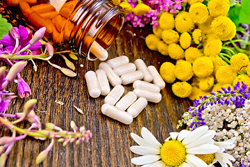 Image showing Capsules in brown jar with flowers on dark board