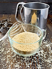 Image showing Flour sesame in cup with sieve on dark board