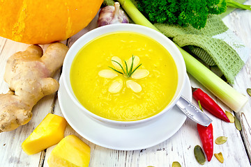 Image showing Soup-puree pumpkin with rosemary in white bowl on board