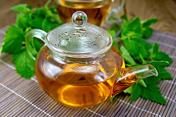 Image showing Tea with mint in glass teapot on wooden board