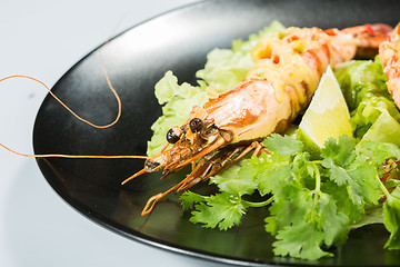 Image showing perfect dish with shrimps on a black plate. seafood