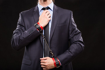 Image showing man in a business suit with leather bound with handcuffs. sex Toys