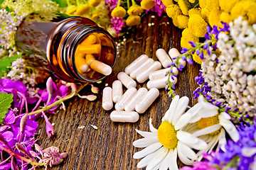 Image showing Capsules in open brown jar on board with flowers