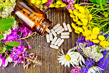 Image showing Capsules in brown jar with flowers on board top