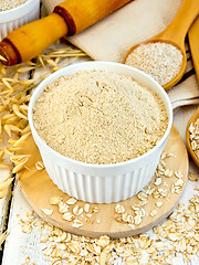 Image showing Flour oat in white bowl with bran and flakes on board