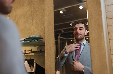 Image showing man trying tie on at mirror in clothing store