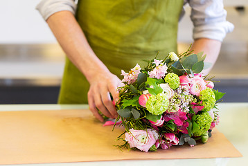 Image showing florist wrapping flowers in paper at flower shop