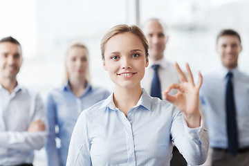 Image showing smiling businesswoman showing ok sign in office