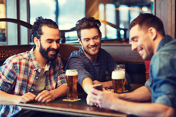 Image showing male friends with smartphone drinking beer at bar