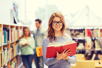 Image showing happy student girl or woman with book in library