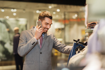 Image showing happy man calling on smartphone at clothing store