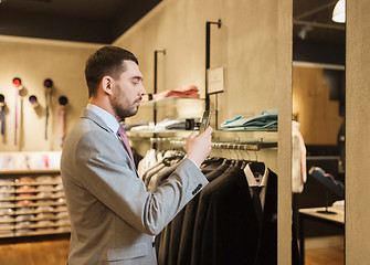 Image showing man in suit with smartphone at clothing store