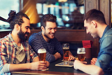 Image showing male friends with tablet pc drinking beer at bar