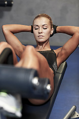 Image showing woman flexing abdominal muscles on bench in gym